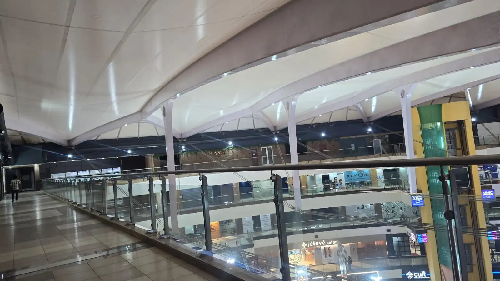 Vasant Square Mall Vasant Kunj — wide view across the central court with the tensioned membrane roof spanning column-free above four levels of shopfronts, Ekra Decor